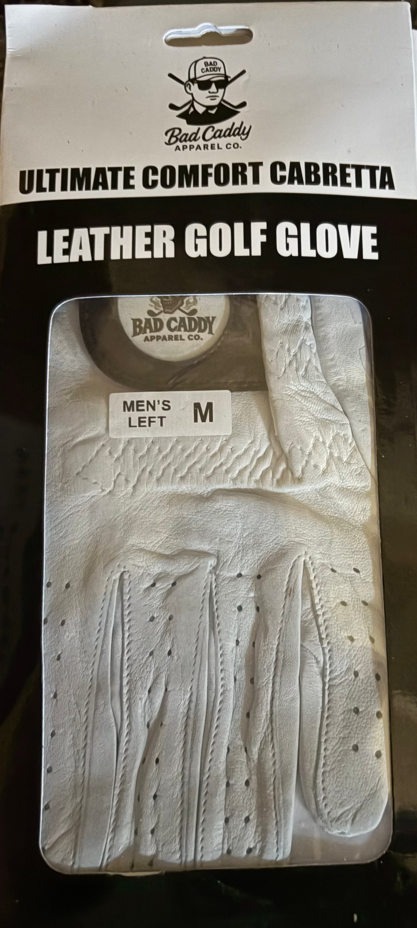 Packaged leather golf glove with 'Bad Caddy' branding on a dark surface