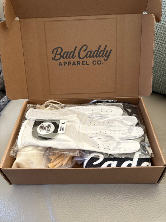 Box from Bad Caddy Apparel Co. containing white shirts and accessories.